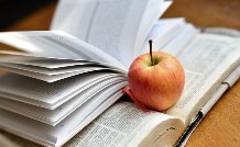 opened Bible, with another study book and an apple