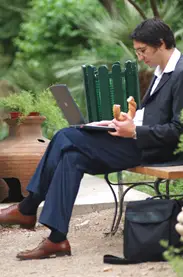 man eating his lunch on a park bench